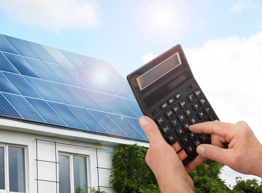 Man,Using,Calculator,Against,House,With,Installed,Solar,Panels.,Renewable